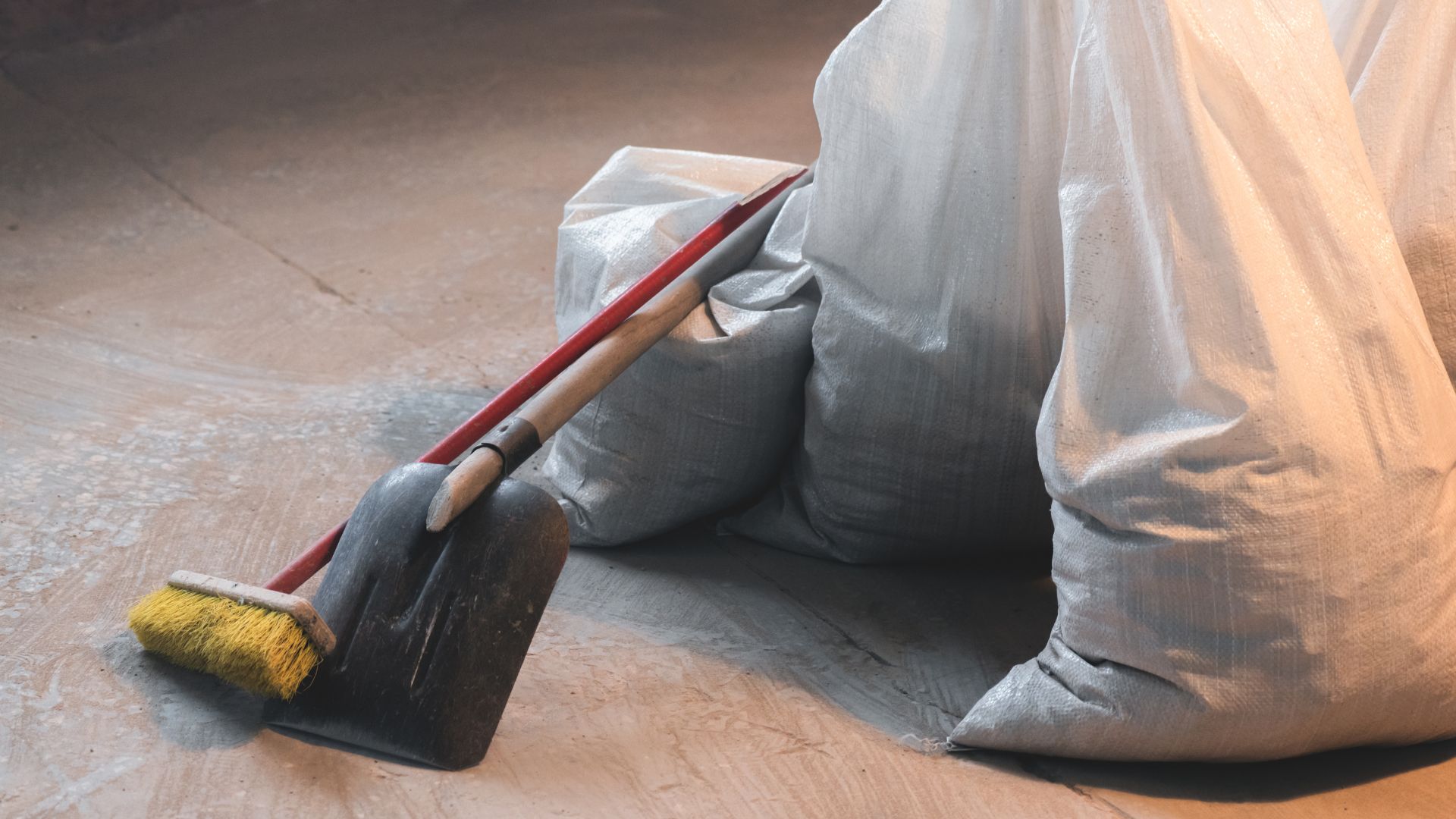 Dustpan, brush, and cloth bags on a wooden floor