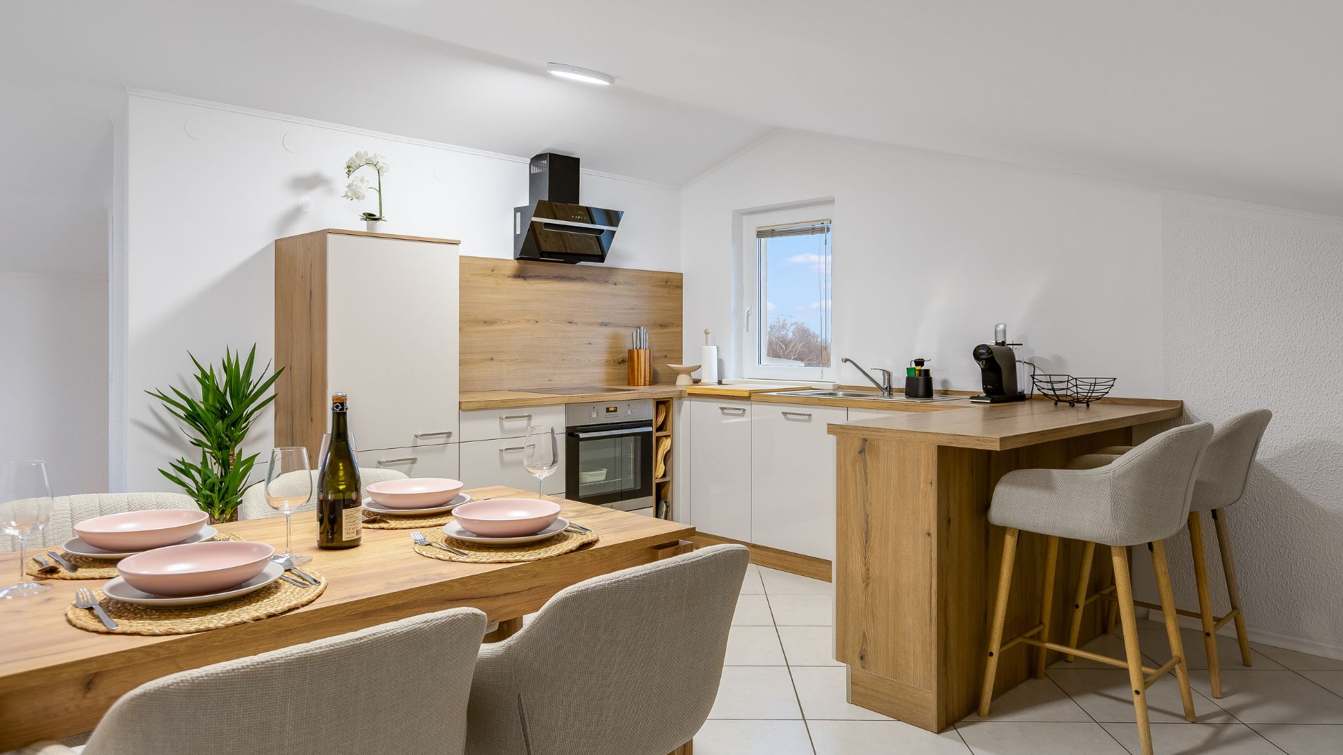 Modern kitchen with wooden accents, set table, and bar stools