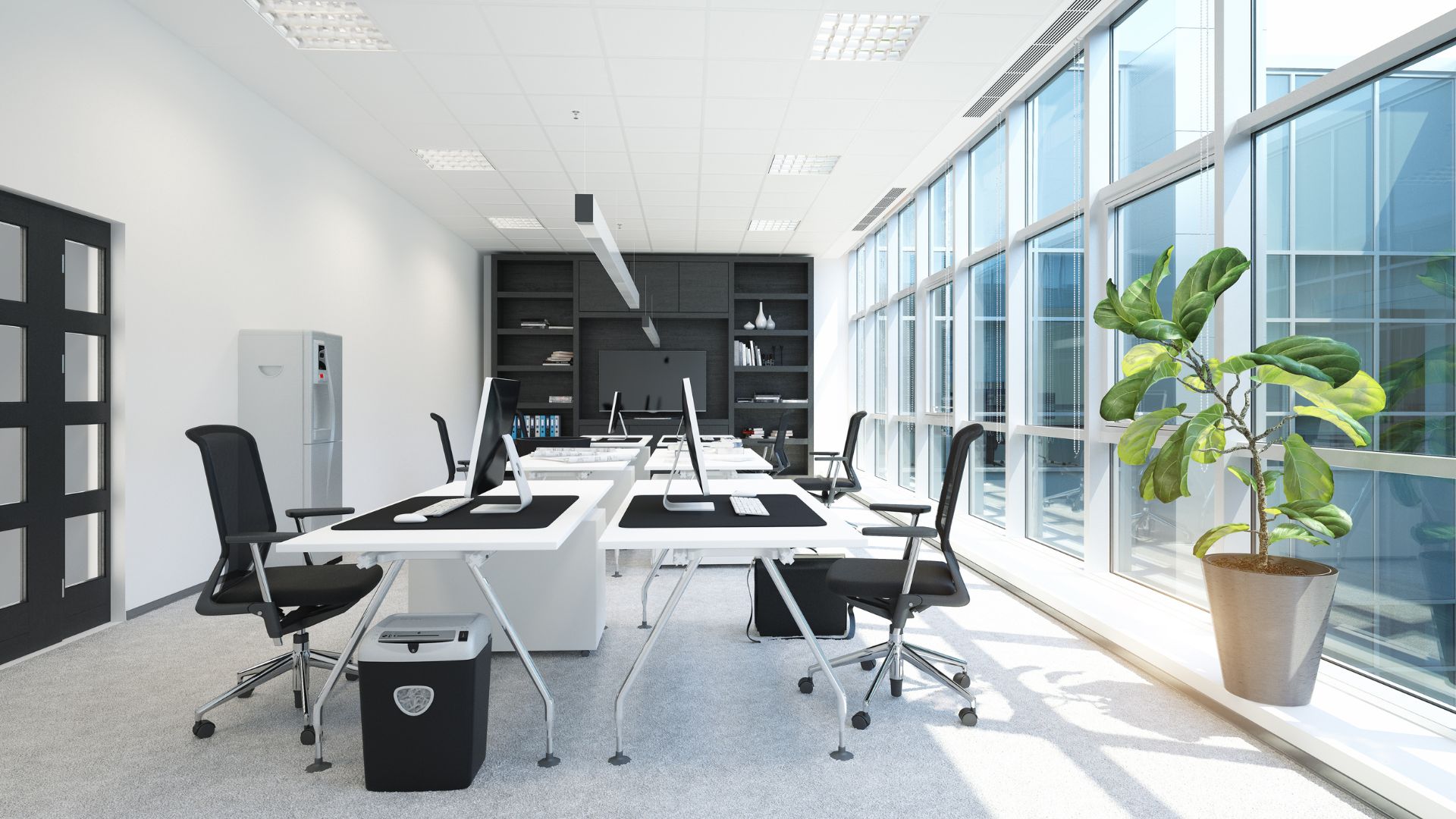 Modern, minimalist office with white desks, black chairs, and large windows