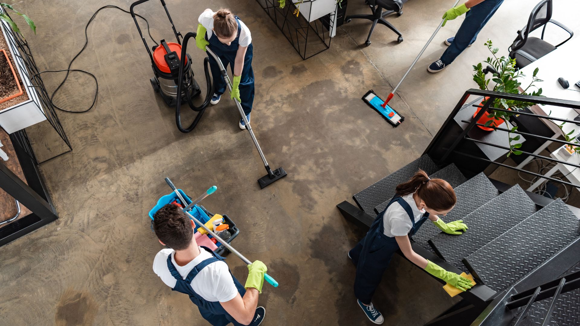 Cleaning team using vacuum and mops to clean an industrial floor workspace